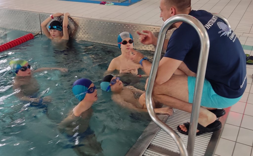 Nauka pływania w grupie na pływalni w Chełmcu. 